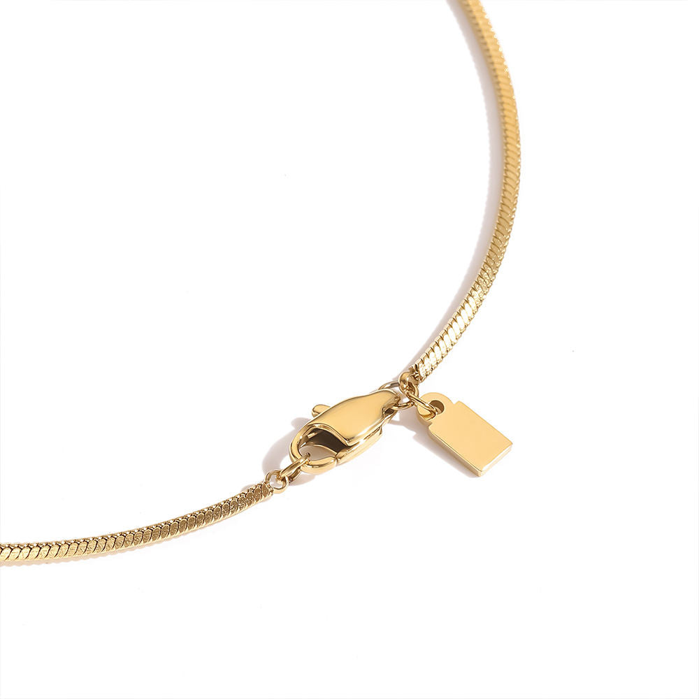 Gold necklace with a clasp and tag on a white background