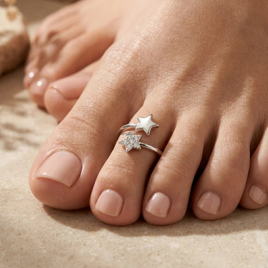 Close-up of a foot wearing a silver star-shaped ring on a sandy background