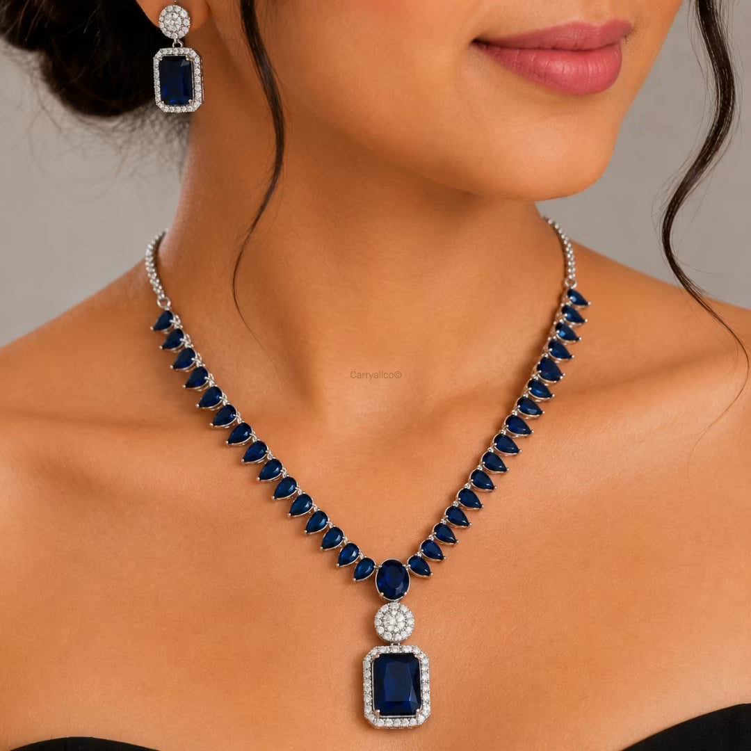 Woman wearing a blue gemstone necklace and earrings on a neutral background