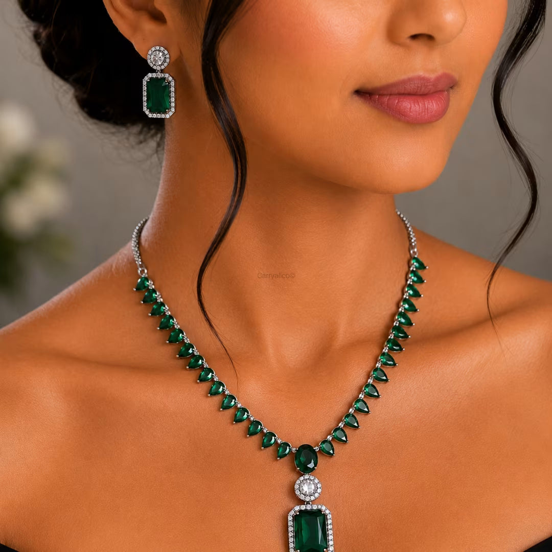 Woman wearing a green emerald necklace and earrings with a blurred background