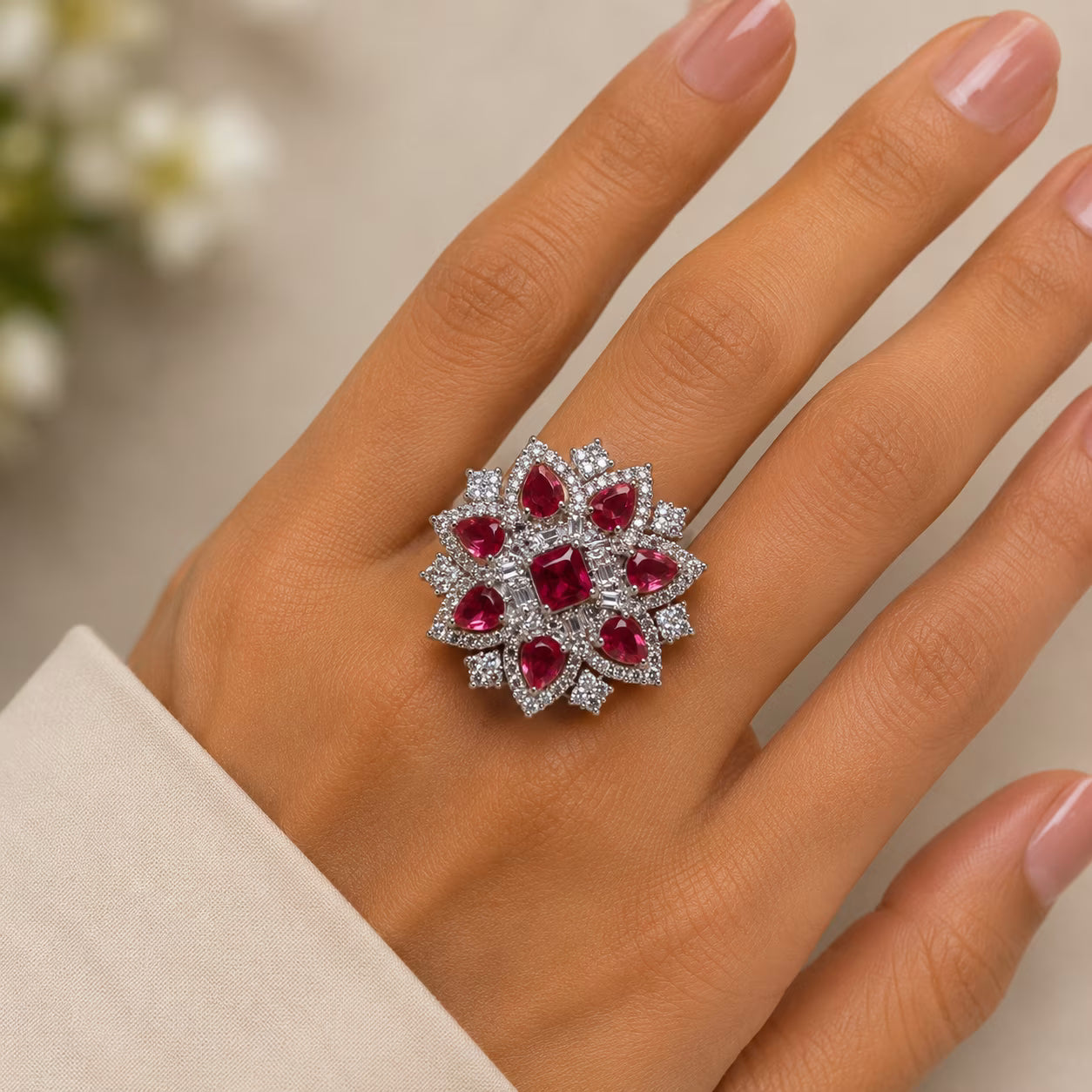 Ring with red gemstones on a hand against a neutral background