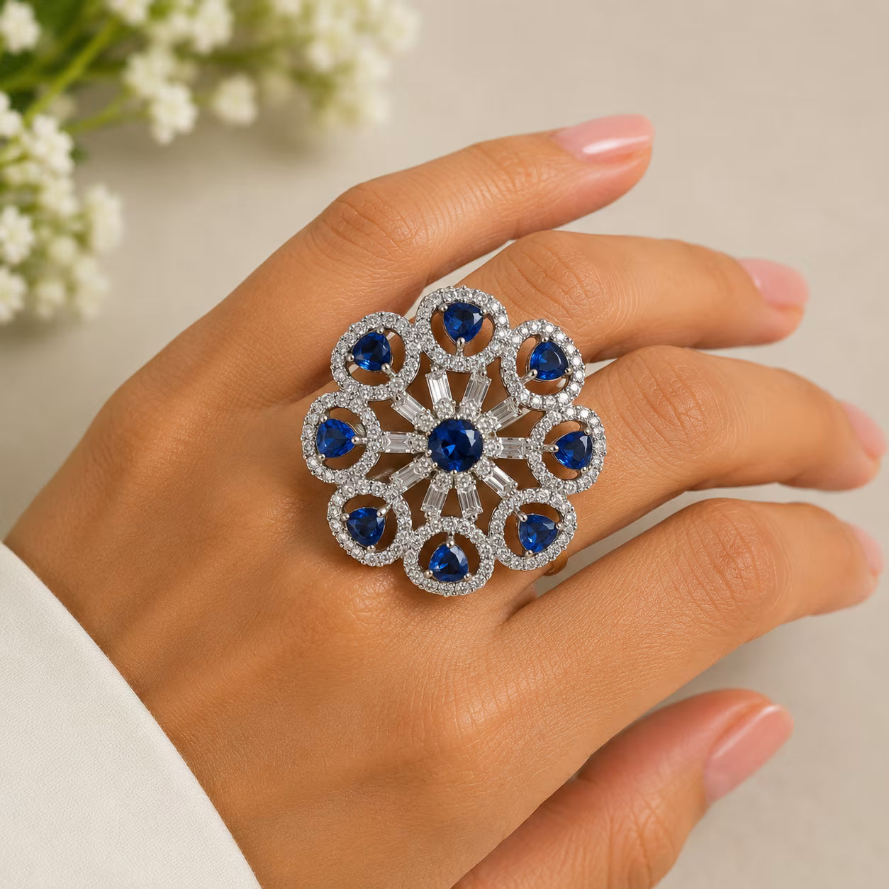 Silver ring with blue gemstones on a hand against a neutral background