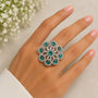 Ring with green gemstones on a hand with a light background