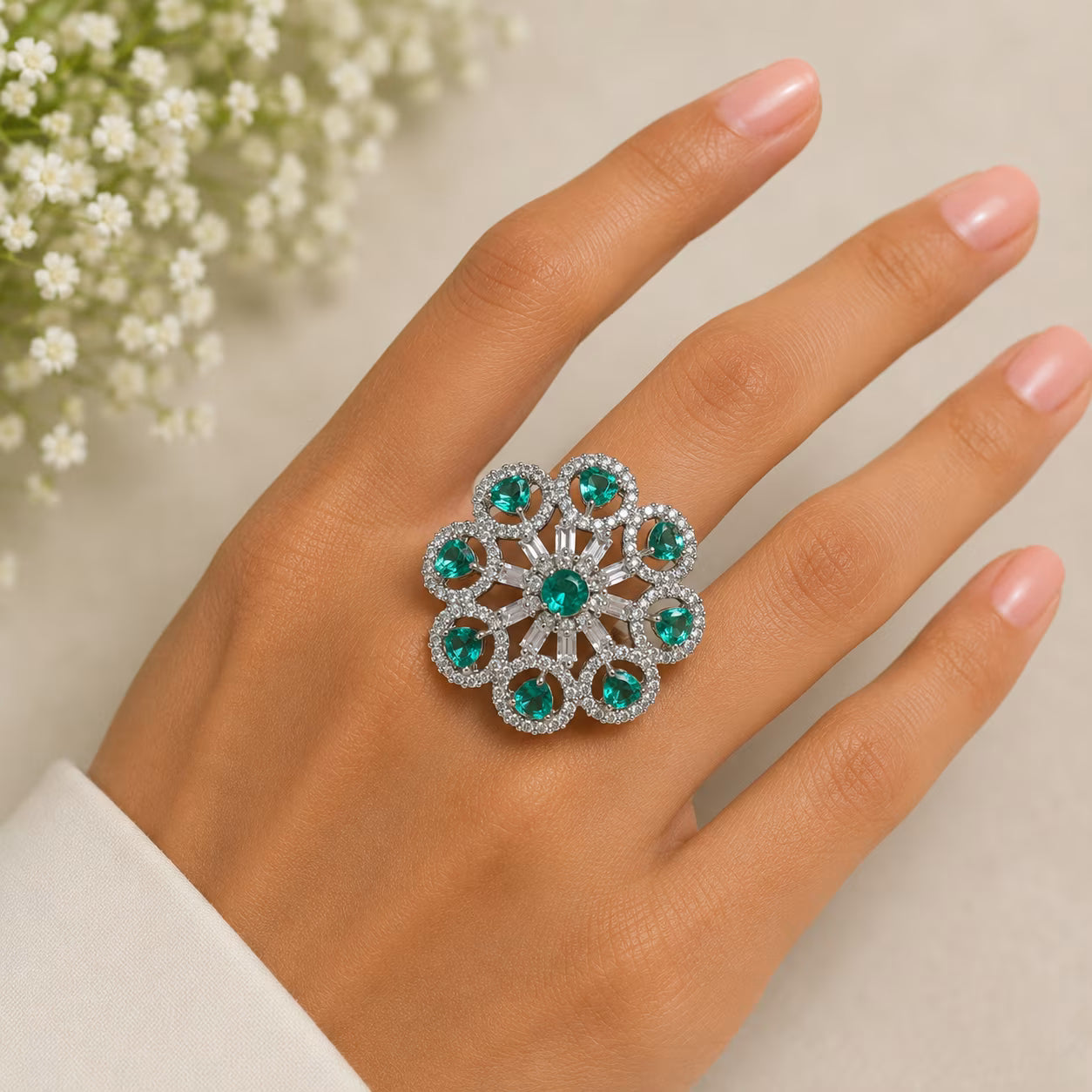 Ring with green gemstones on a hand with a light background
