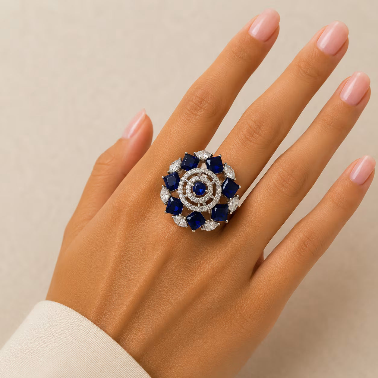 Elegant ring with blue gemstones on a hand against a neutral background