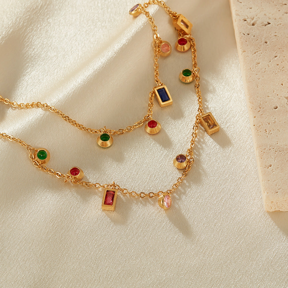 Gold necklace with colorful gemstones on a beige fabric background