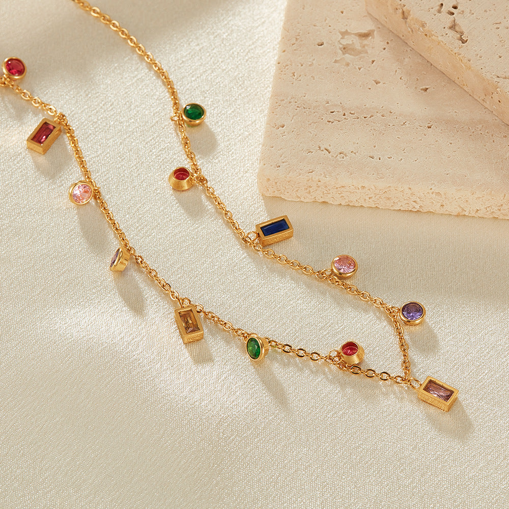Gold necklace with colorful gemstones on a beige surface