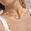 Close-up of a woman wearing a colorful gemstone necklace on a plain background
