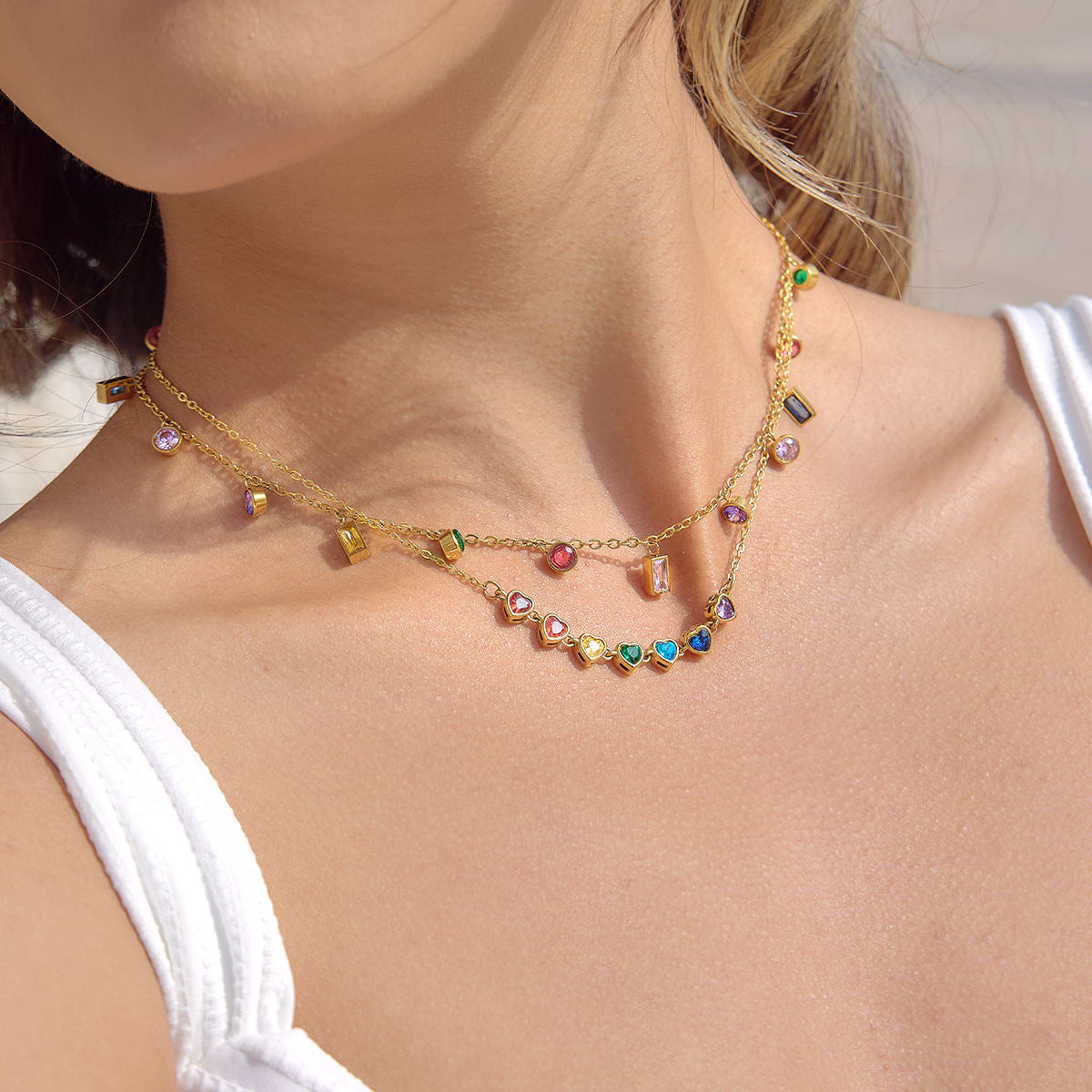 Close-up of a woman wearing a colorful gemstone necklace on a plain background