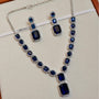 Jewelry set with necklace and earrings featuring blue gemstones on a white background.