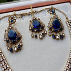 Gold and blue gemstone necklace on a white cushion