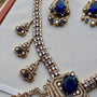 Gold necklace with blue gemstones on a light gray background