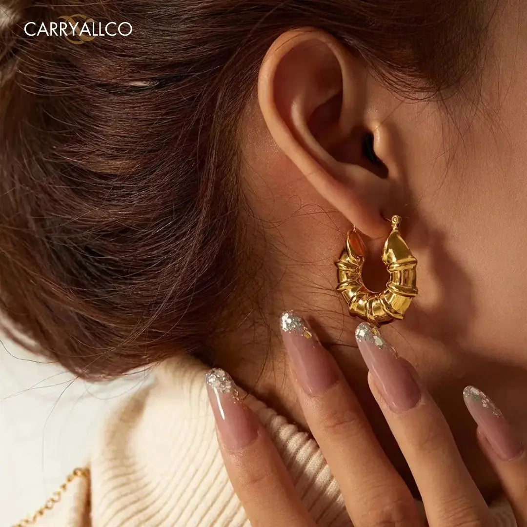 Close-up of a person wearing a gold hoop earring with a blurred background