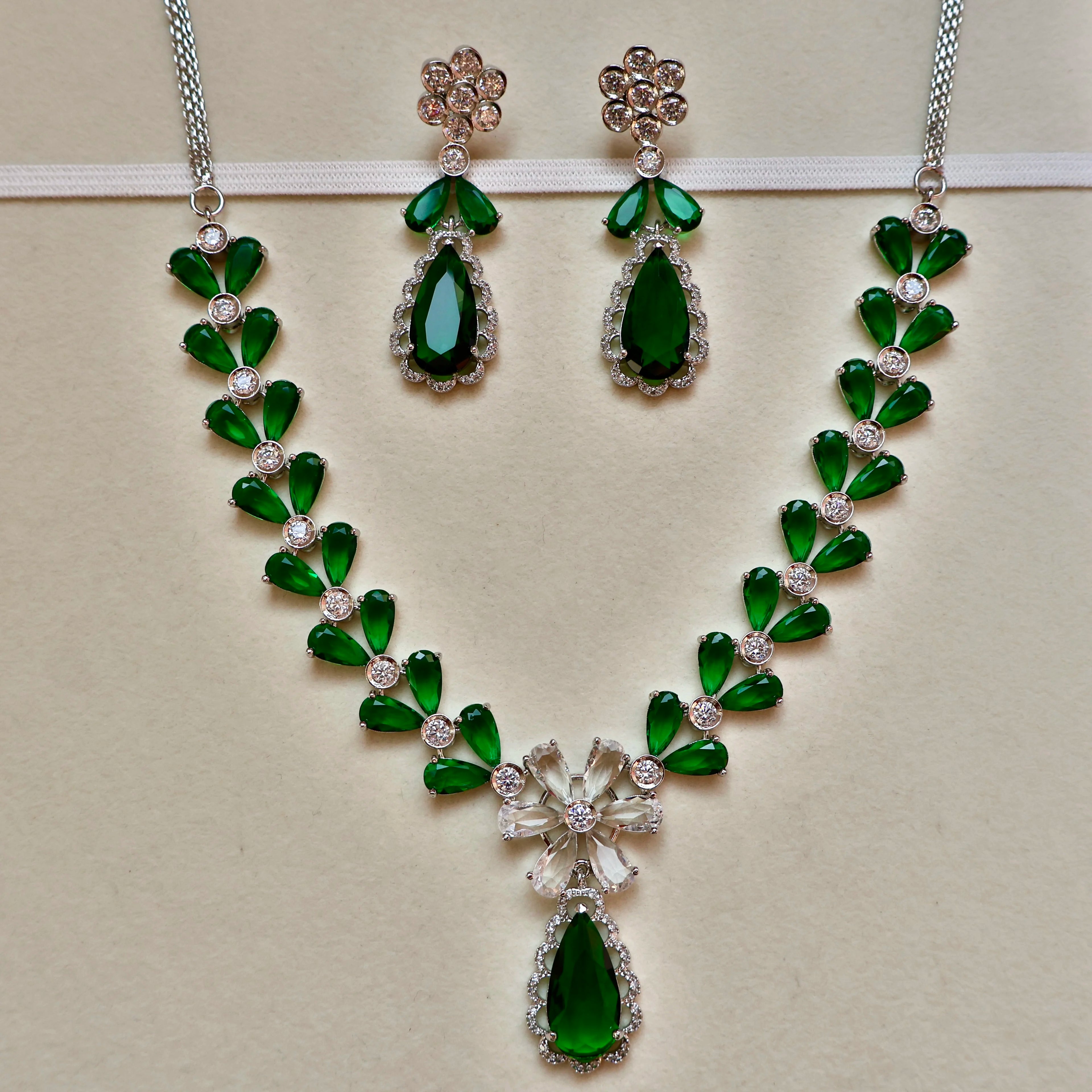 Green gemstone necklace and earrings on a light background