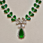 Green gemstone necklace with silver accents on a beige background