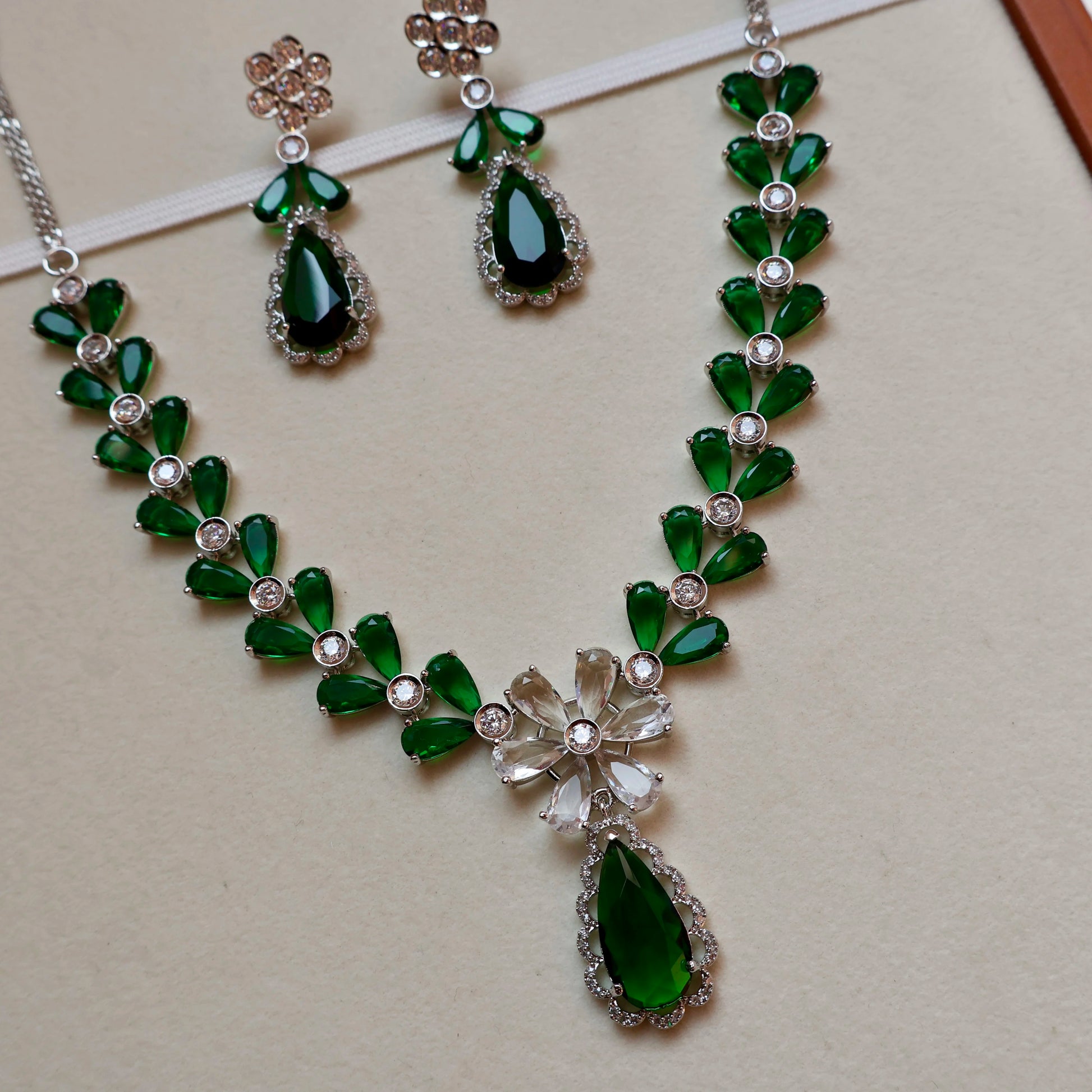 Green gemstone necklace and earrings on a beige background