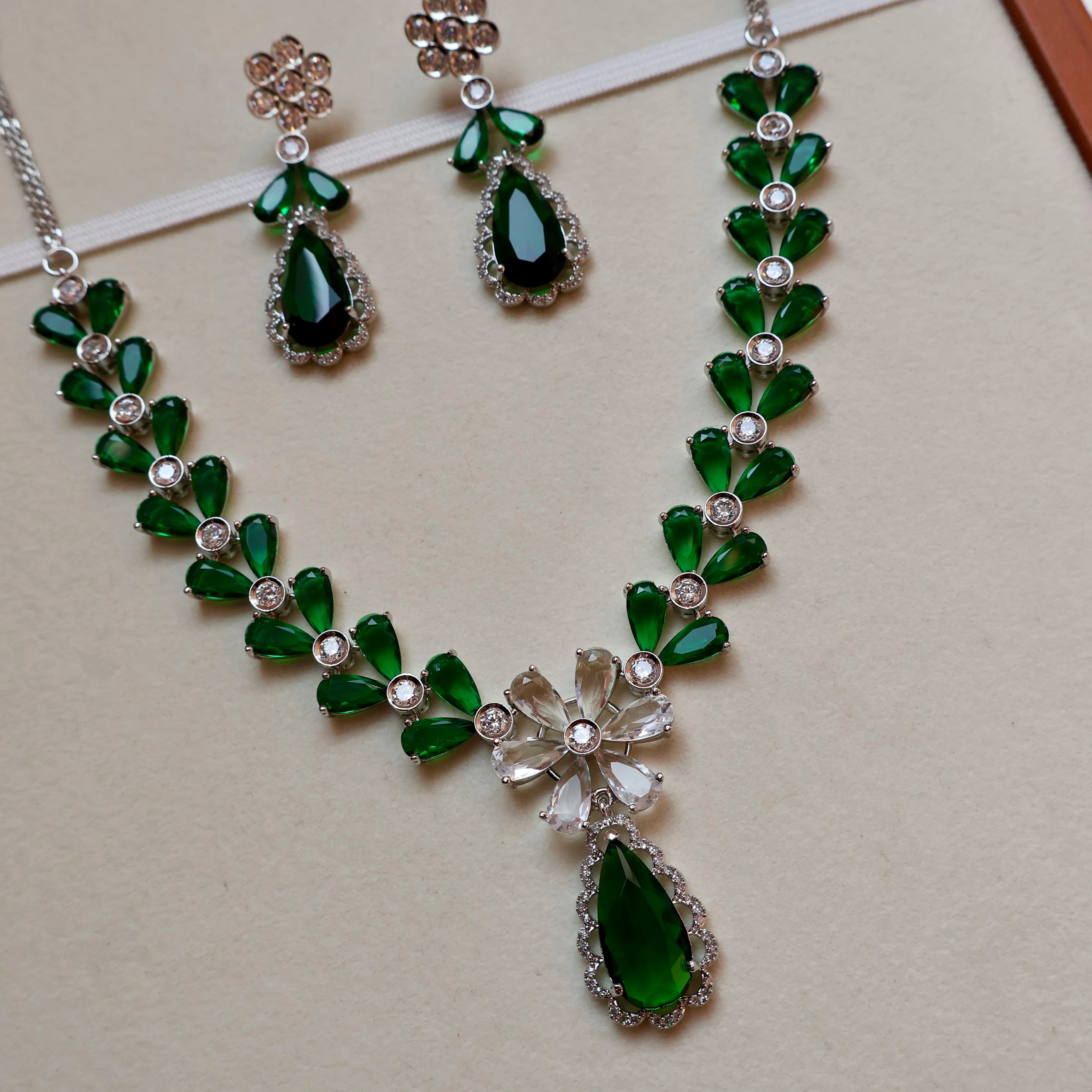 Green gemstone necklace and earrings on a beige background