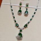 Jewelry set with necklace and earrings featuring green gemstones on a beige background