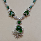 Necklace with green gemstones and silver accents on a beige background