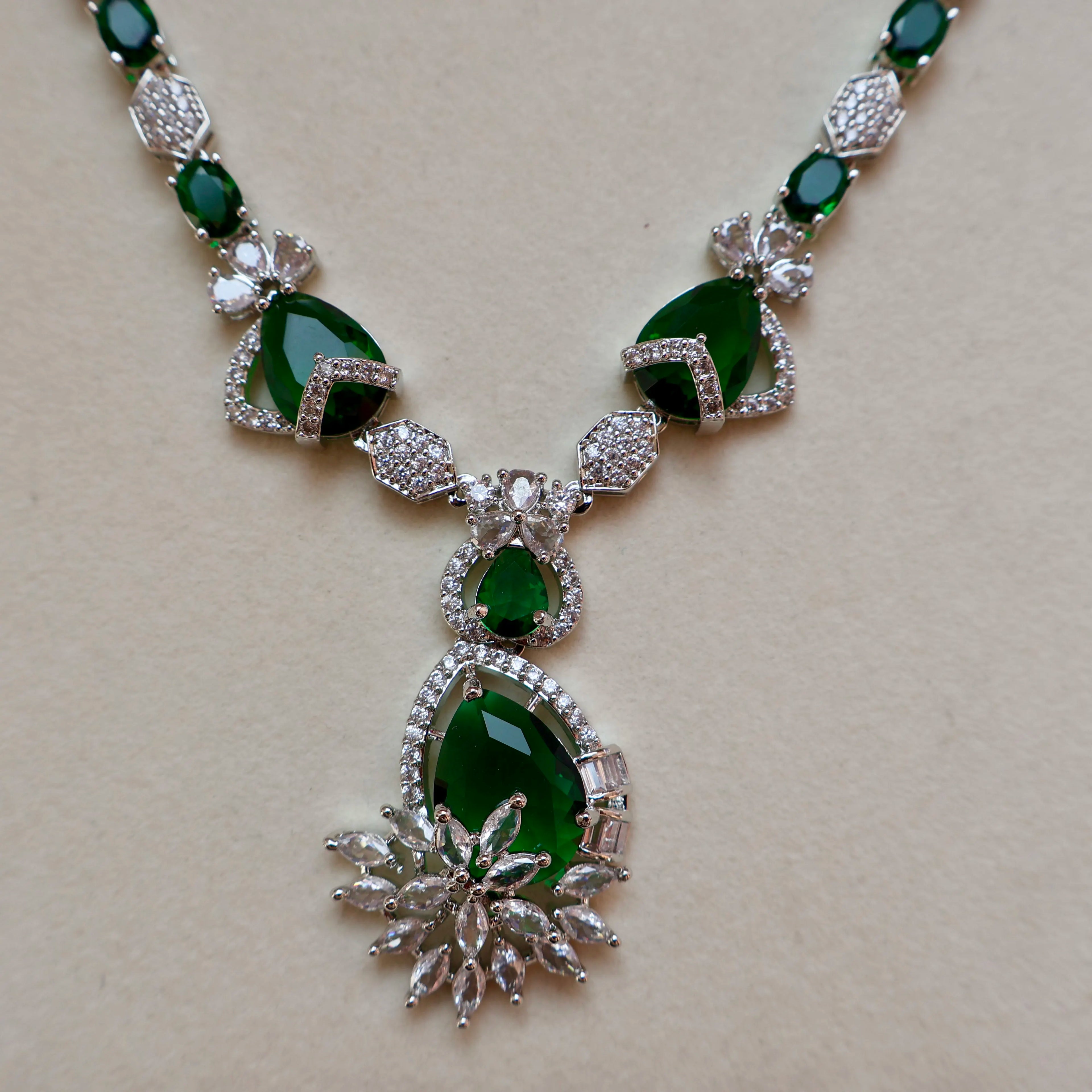 Necklace with green gemstones and silver accents on a beige background