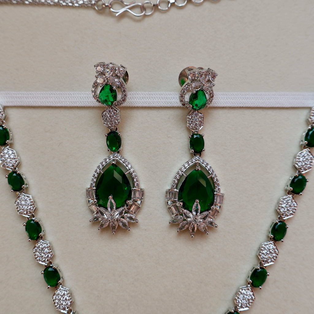 Green gemstone earrings and necklace set on a beige background