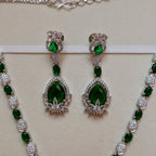Green gemstone earrings and necklace set on a beige background