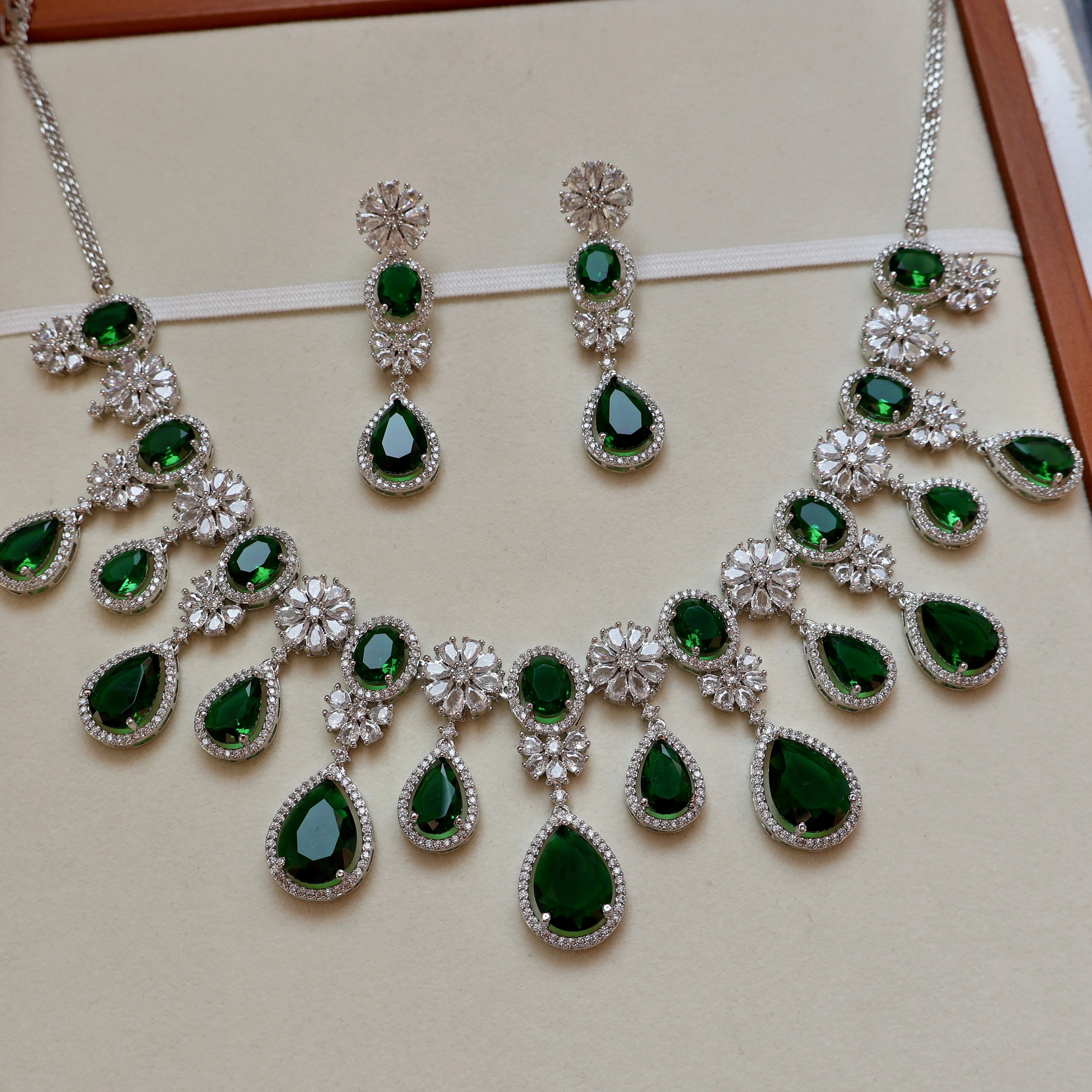 Jewelry set with green gemstones on a beige background