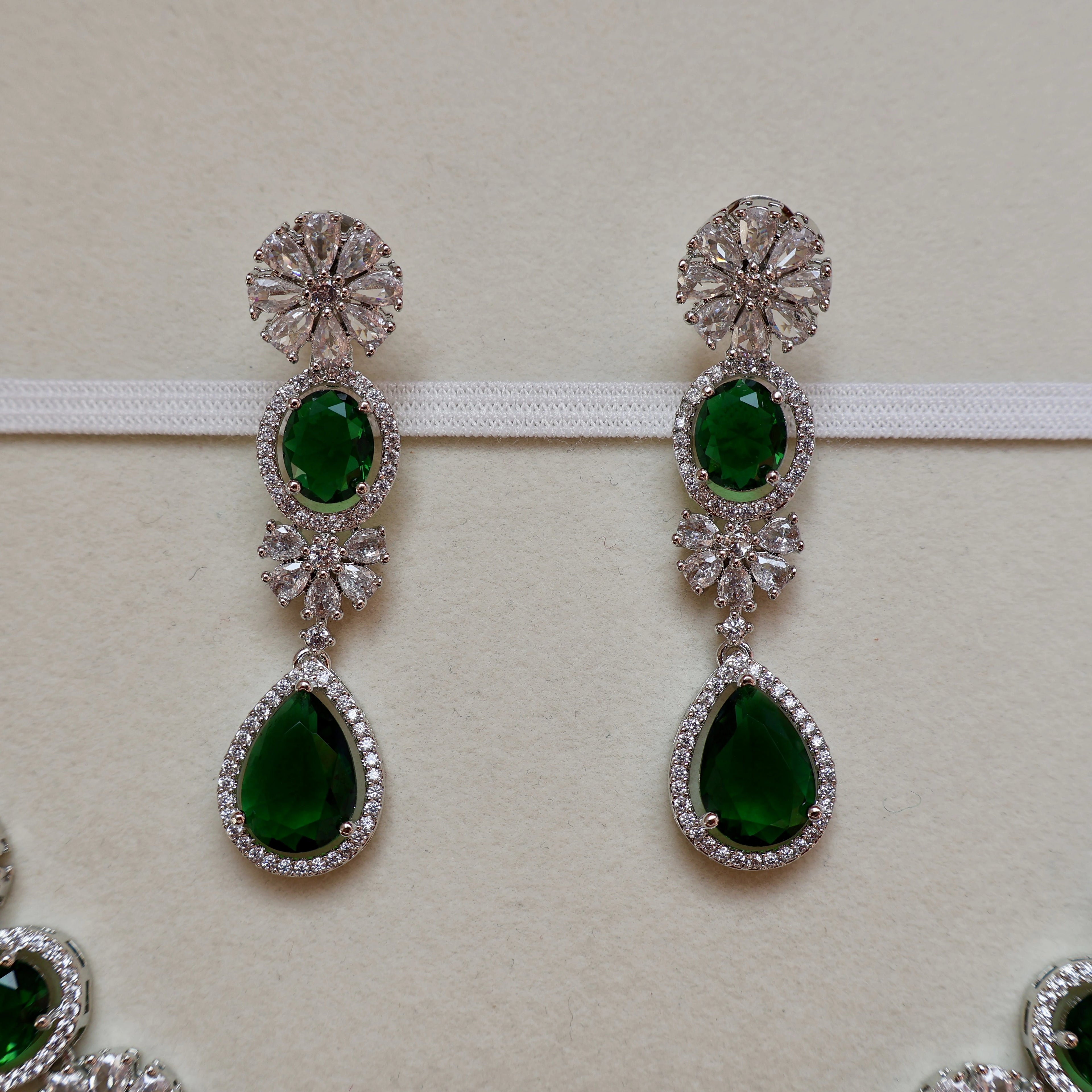 Pair of green gemstone earrings with silver detailing on a light background