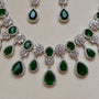 Jewelry set with green gemstones and silver accents on a beige background