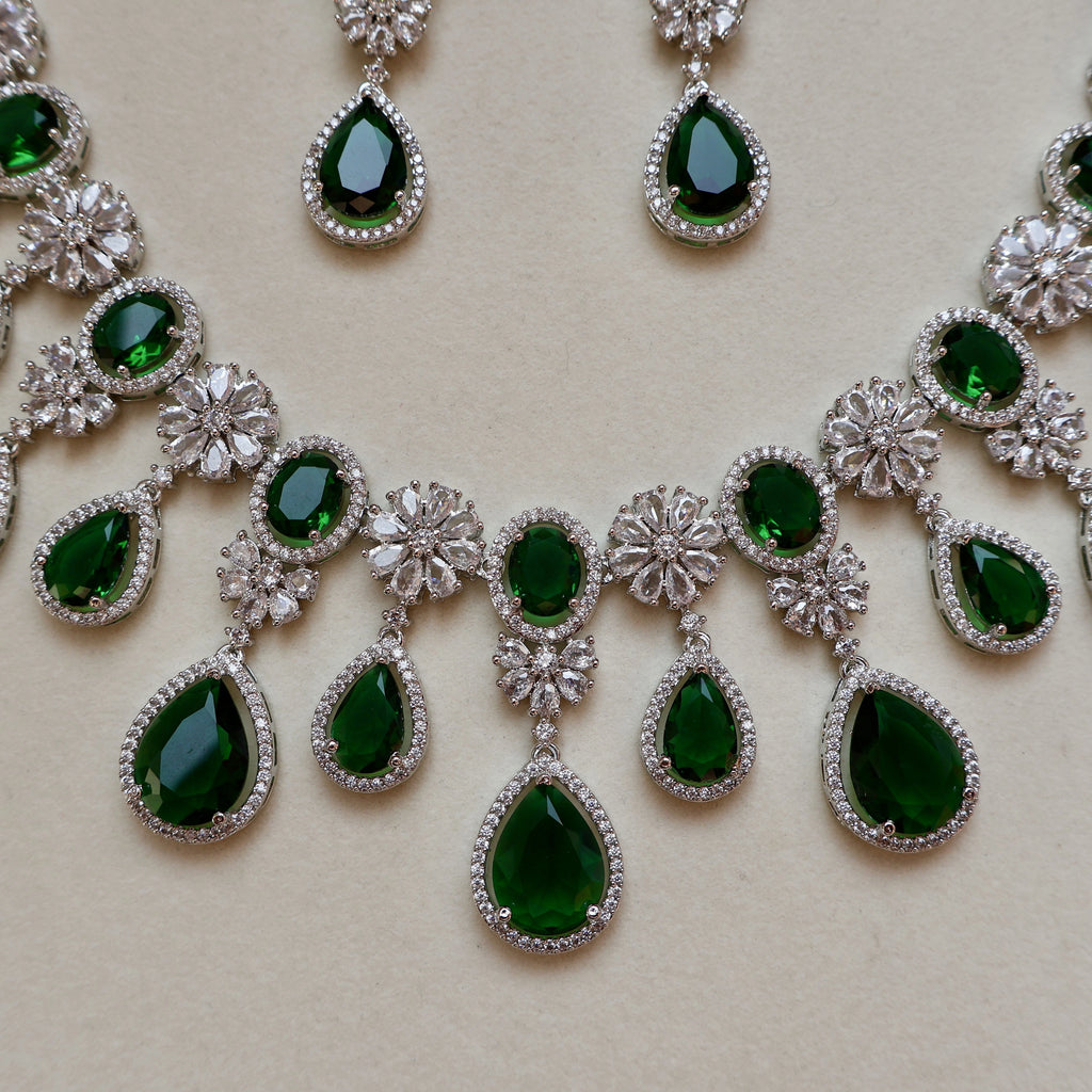 Jewelry set with green gemstones and silver accents on a beige background