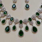 Jewelry set with green gemstones and silver accents on a beige background