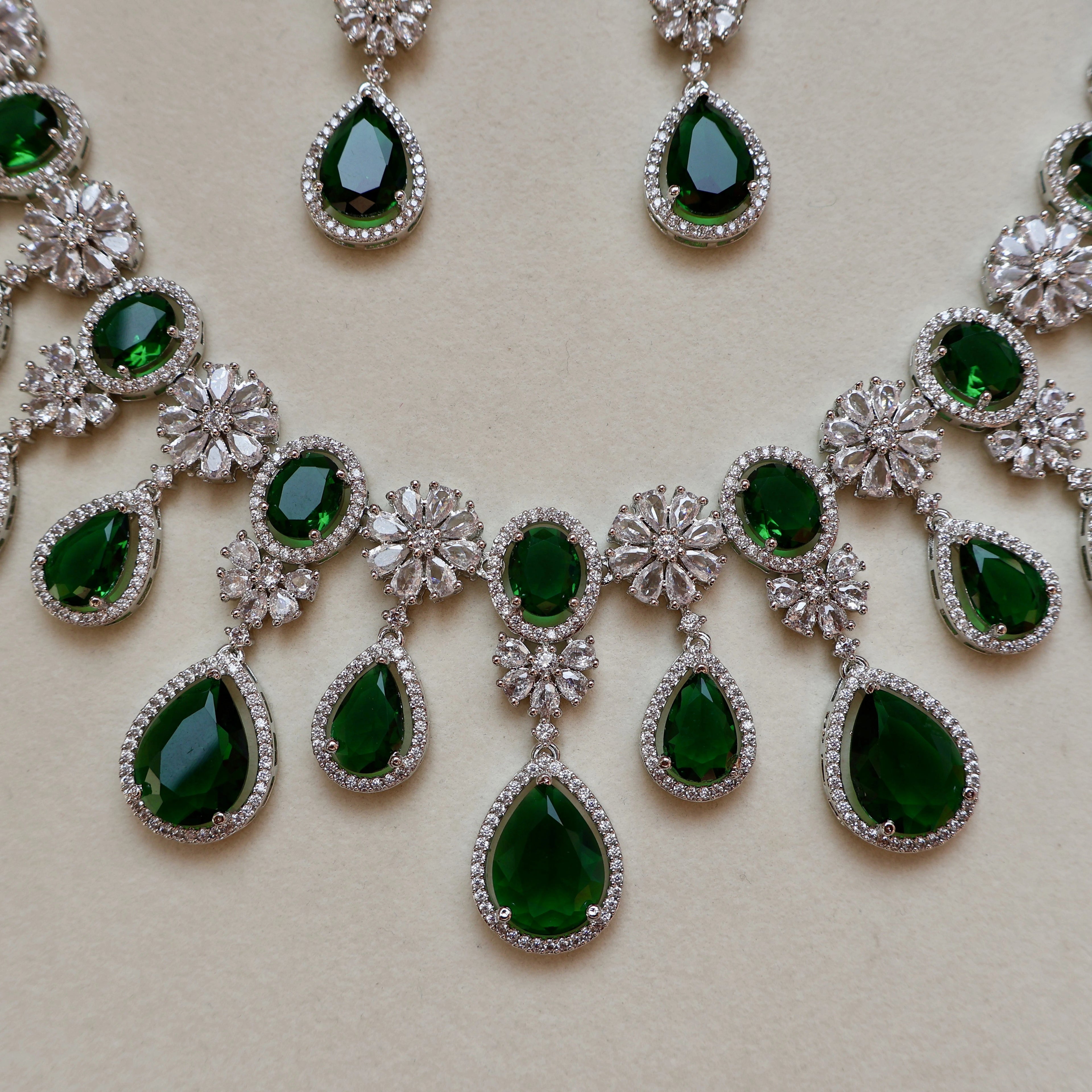 Jewelry set with green gemstones and silver accents on a beige background