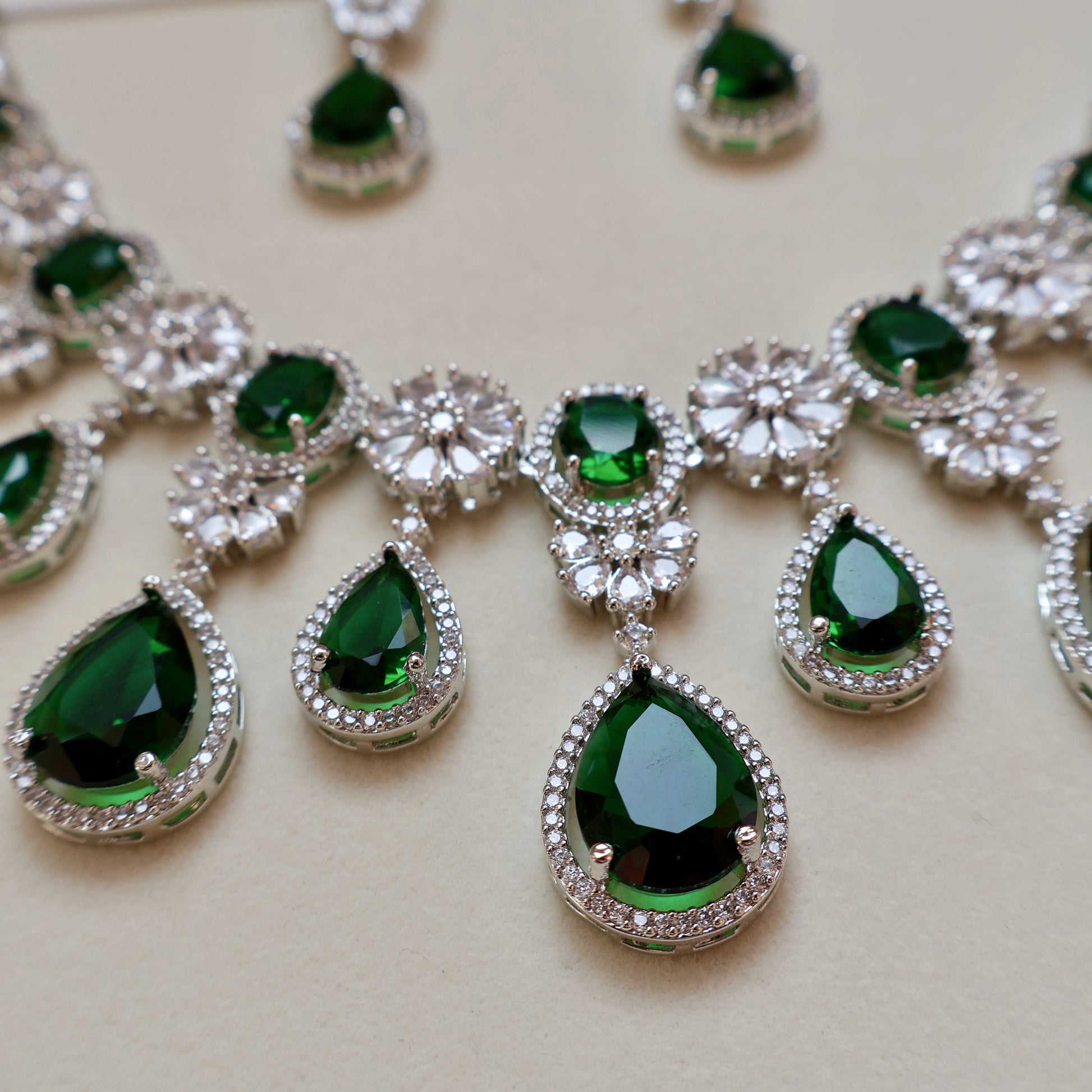 Necklace with green teardrop-shaped gemstones and silver accents on a light background