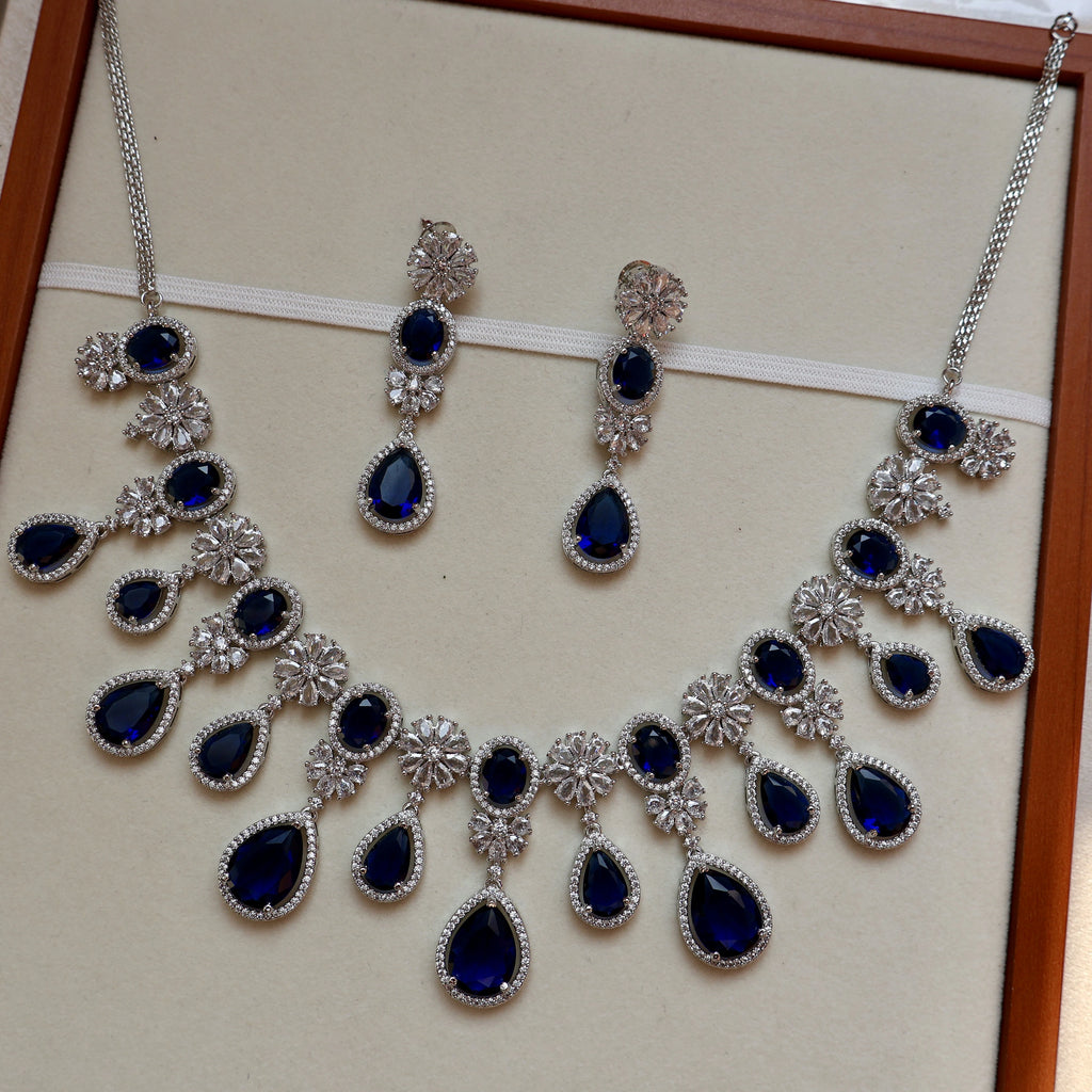 Jewelry set with necklace and earrings featuring blue stones on a beige background