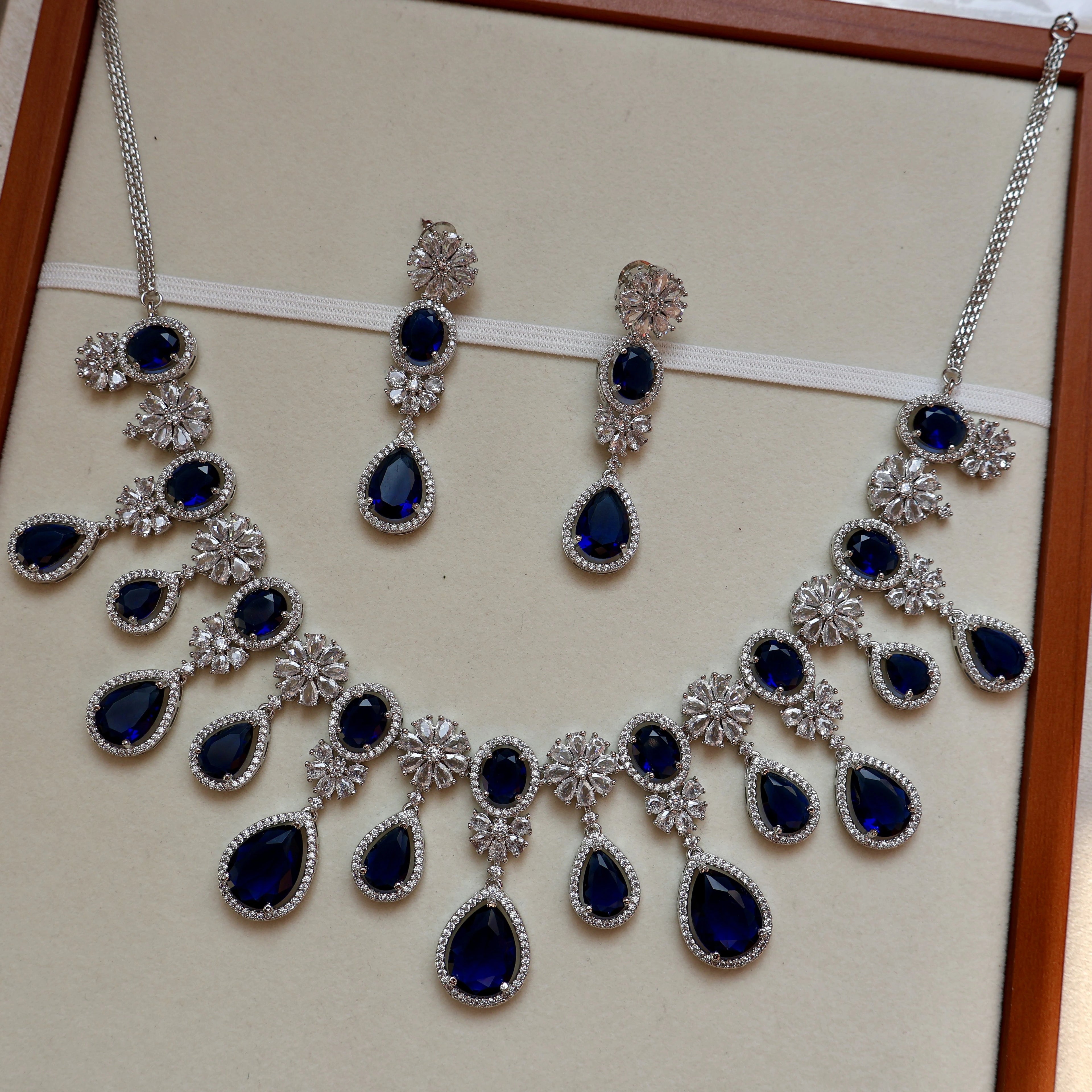 Jewelry set with necklace and earrings featuring blue stones on a beige background