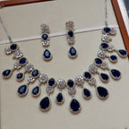 Jewelry set with necklace and earrings featuring blue stones on a beige background