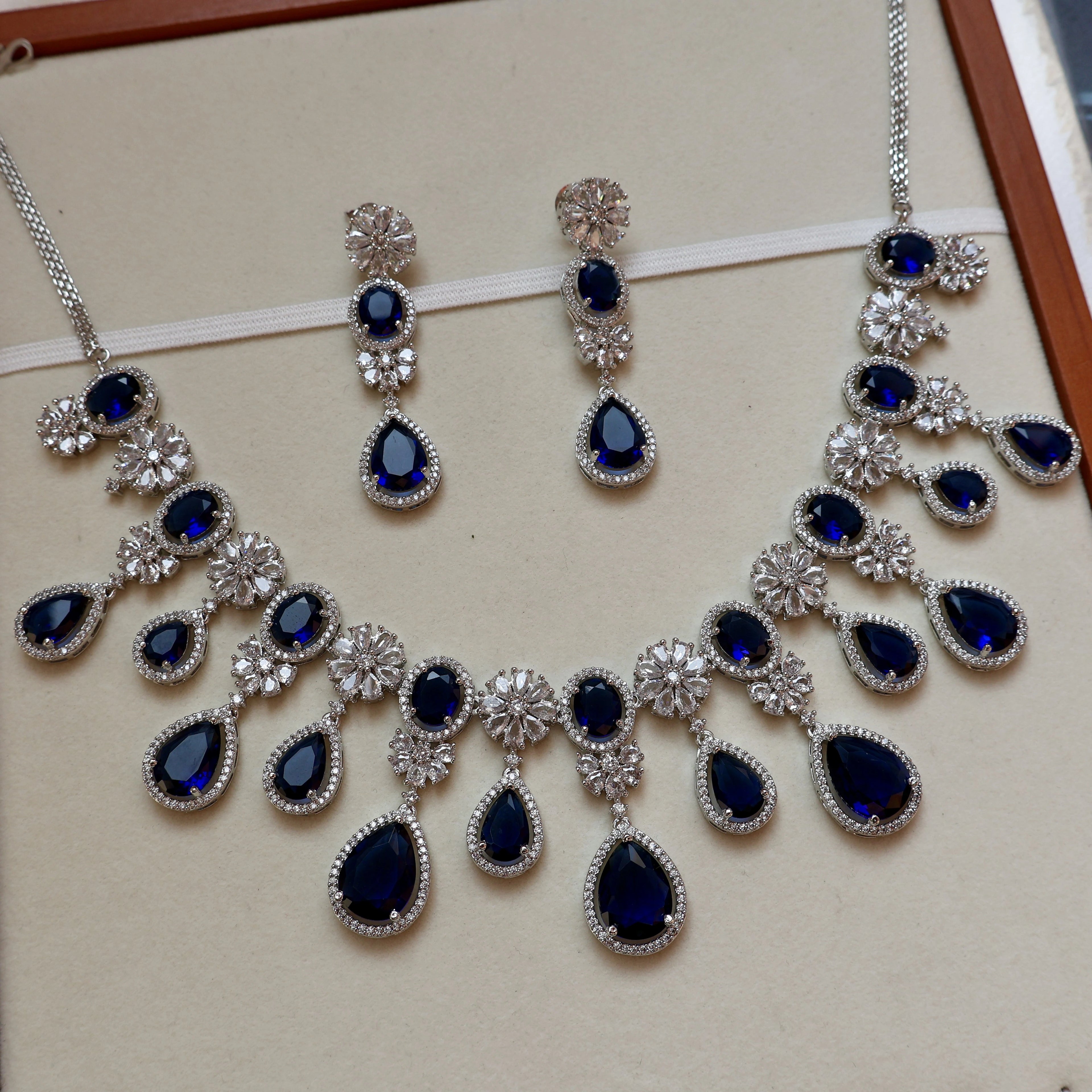 Jewelry set with necklace and earrings featuring blue stones on a beige background
