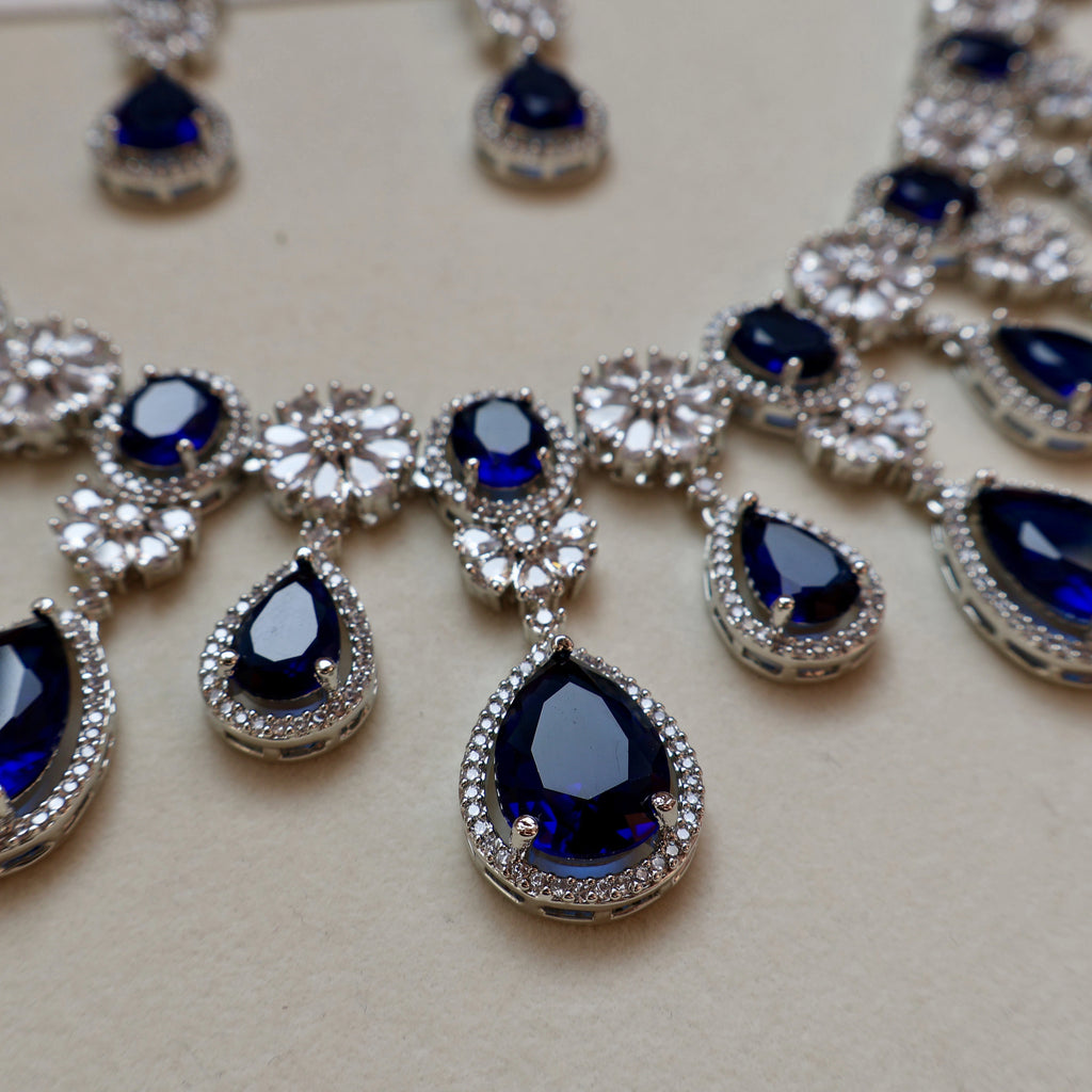 Jewelry set with blue teardrop stones and silver accents on a light background