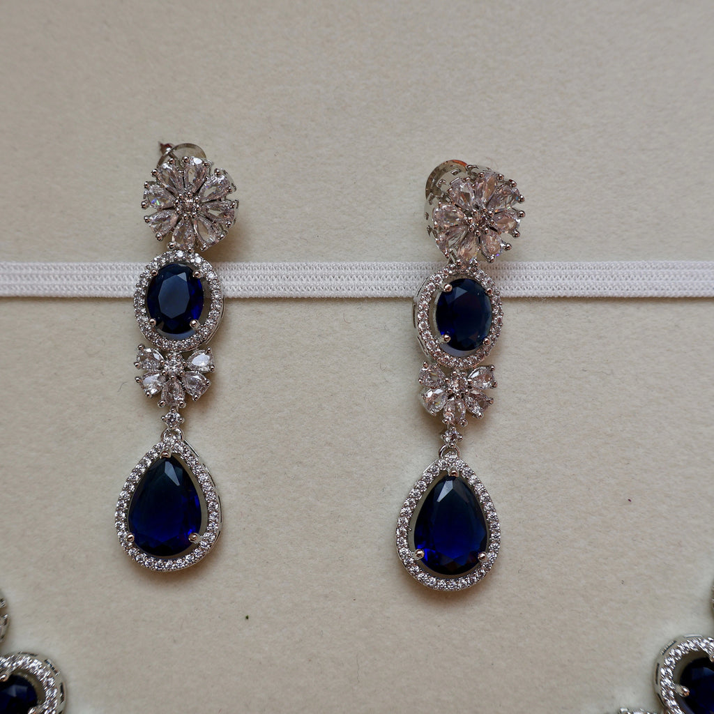 Pair of silver earrings with blue gemstones on a white background