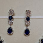 Pair of silver earrings with blue gemstones on a white background