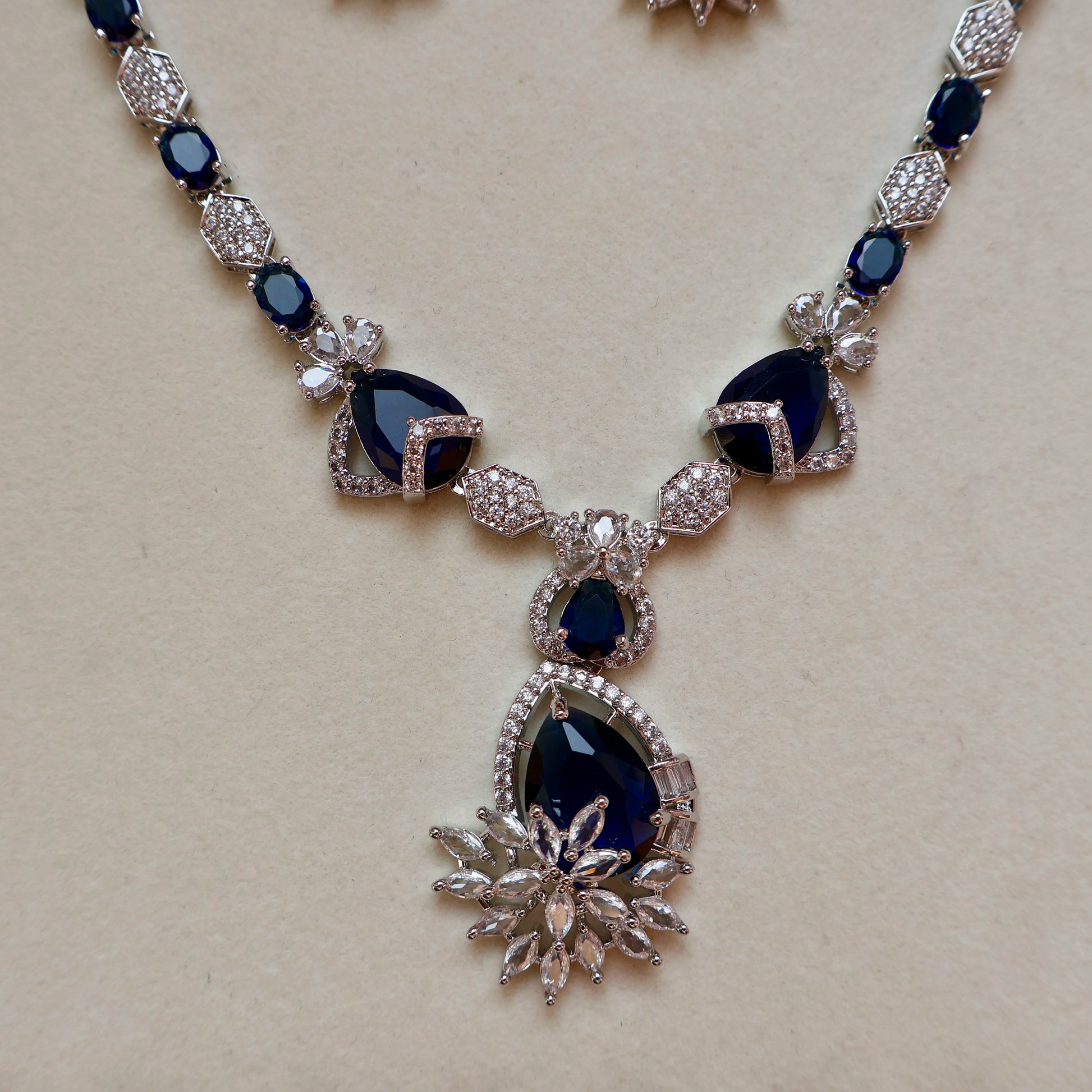 Necklace with blue gemstones and silver accents on a beige background