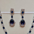 Pair of blue gemstone earrings on a beige background