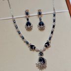 Jewelry set with necklace and earrings featuring blue stones on a beige background