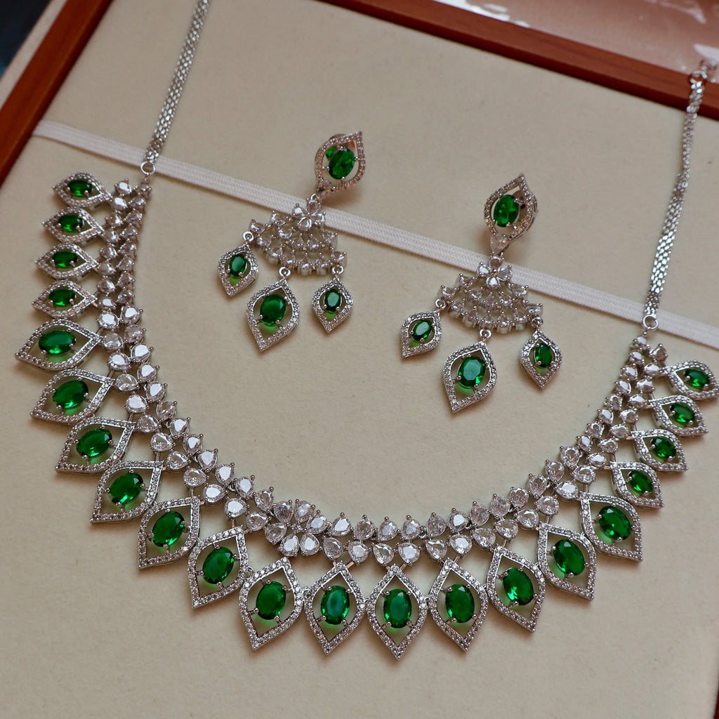 Jewelry set with necklace and earrings featuring green gemstones on a beige background