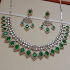 Jewelry set with necklace and earrings featuring green gemstones on a beige background