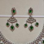 Pair of silver earrings with green gemstones on a beige background