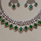 Necklace with green gemstones and matching earrings on a beige background