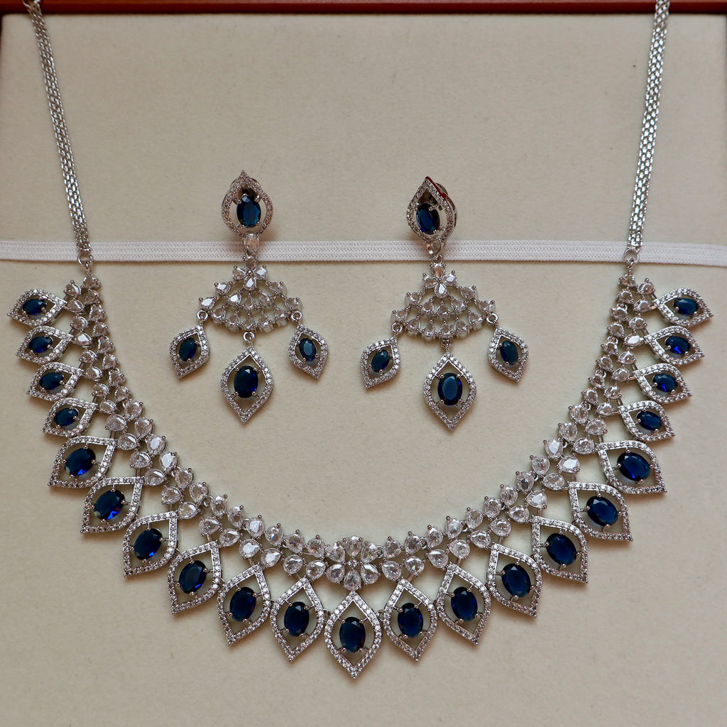 Silver necklace with blue gemstones and matching earrings on a beige background