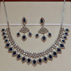 Silver necklace with blue gemstones and matching earrings on a beige background