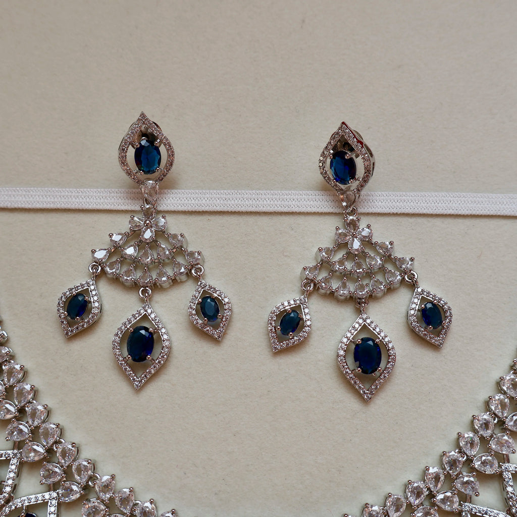 Pair of silver earrings with blue gemstones on a beige background